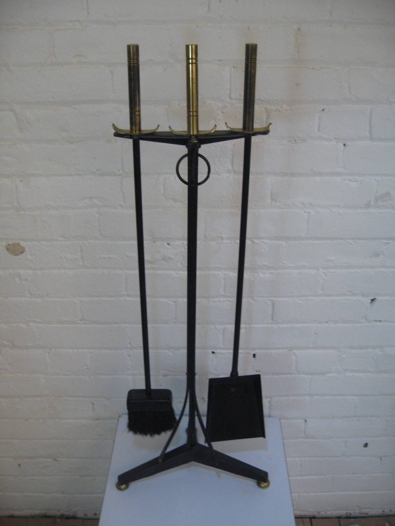 Fine set of modern fireplace tools.  Complete set consisting of brush, tongs, and shovel with tripod stand.  The brass handles are reminiscent of Tommi Parzinger designs for Dorlyn Silversmiths.  Circa 1950-60.
