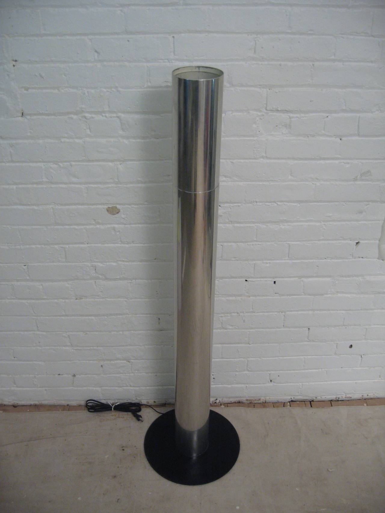 Mid-Century Modern aluminium and steel floor lamp. The outer cylinder is made of polished aluminum and the base is steel with a black enamel finish. The touch lamp has no switches. Measure: 13