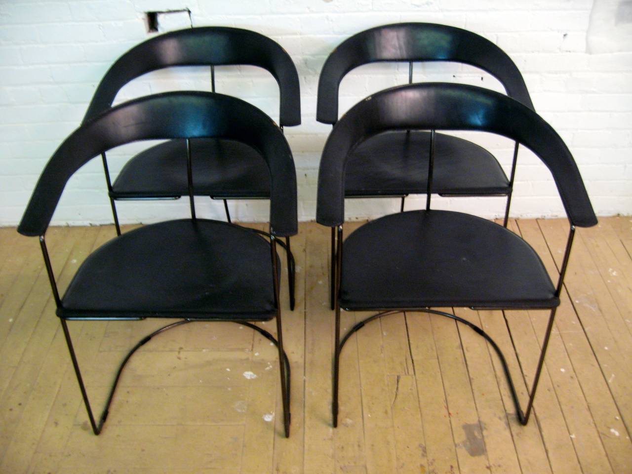 Set of four Arrben Italy hard leather dining armchairs.  Circa 1980.  Black enameled steel and leather cantilever construction with rear support rod.  Excellent, heavy duty tanned and stitched black leather seats and backs.  Embossed signature under