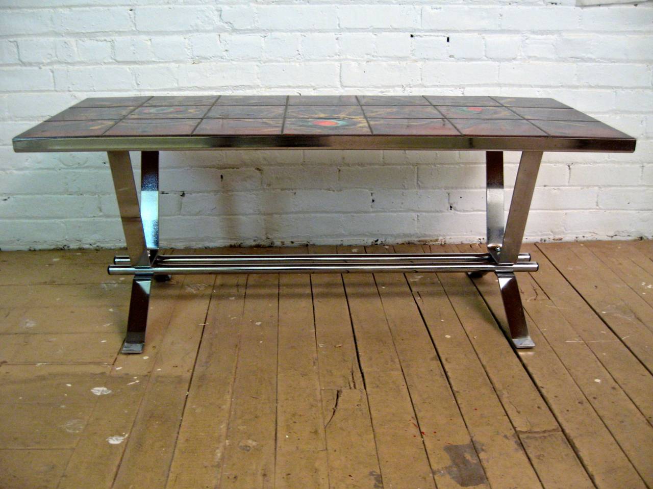 Wonderful high glazed sun burst pattern tile top coffee table.  Chrome metal stretcher base with 21 individually set tiles.  The tiles are decorated in golden brown, bright red, aqua, green, black, orange with copper dust inclusions. Designed by