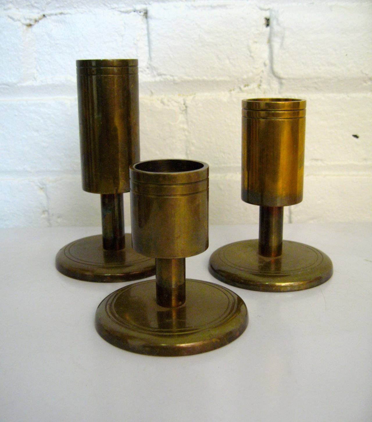 Three solid brass tiered candle holders.  Signed on bottom with gold foil label, Dan Present Ltd., Denmark.  Varying sizes with 3