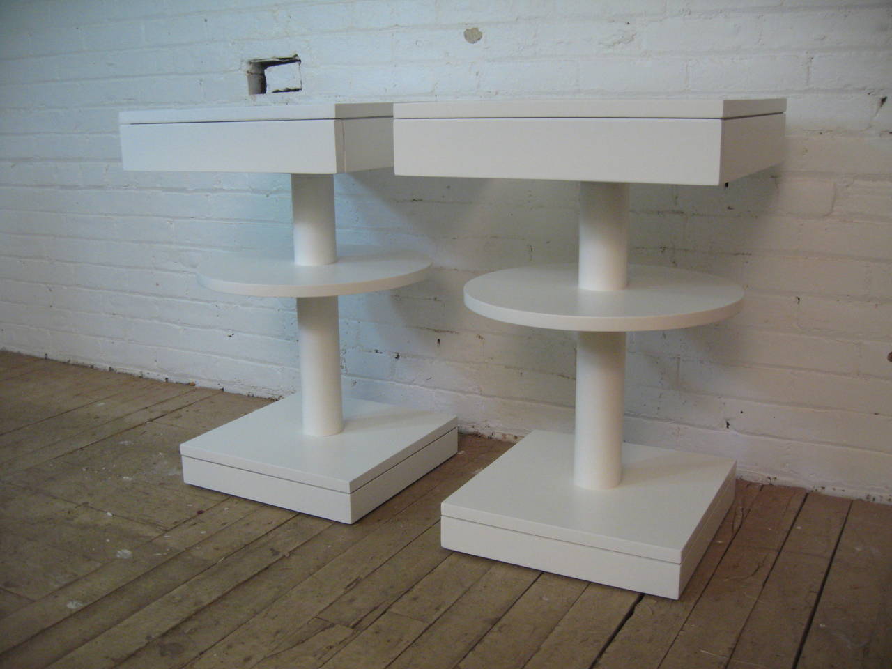 Truly amazing vintage single-drawer end tables. Lacquered in a semi gloss white. Drawer interiors are solid oak. The tops measure 18" x 18" while the bases measure 15" x 15". These geometric oddities make the perfect
