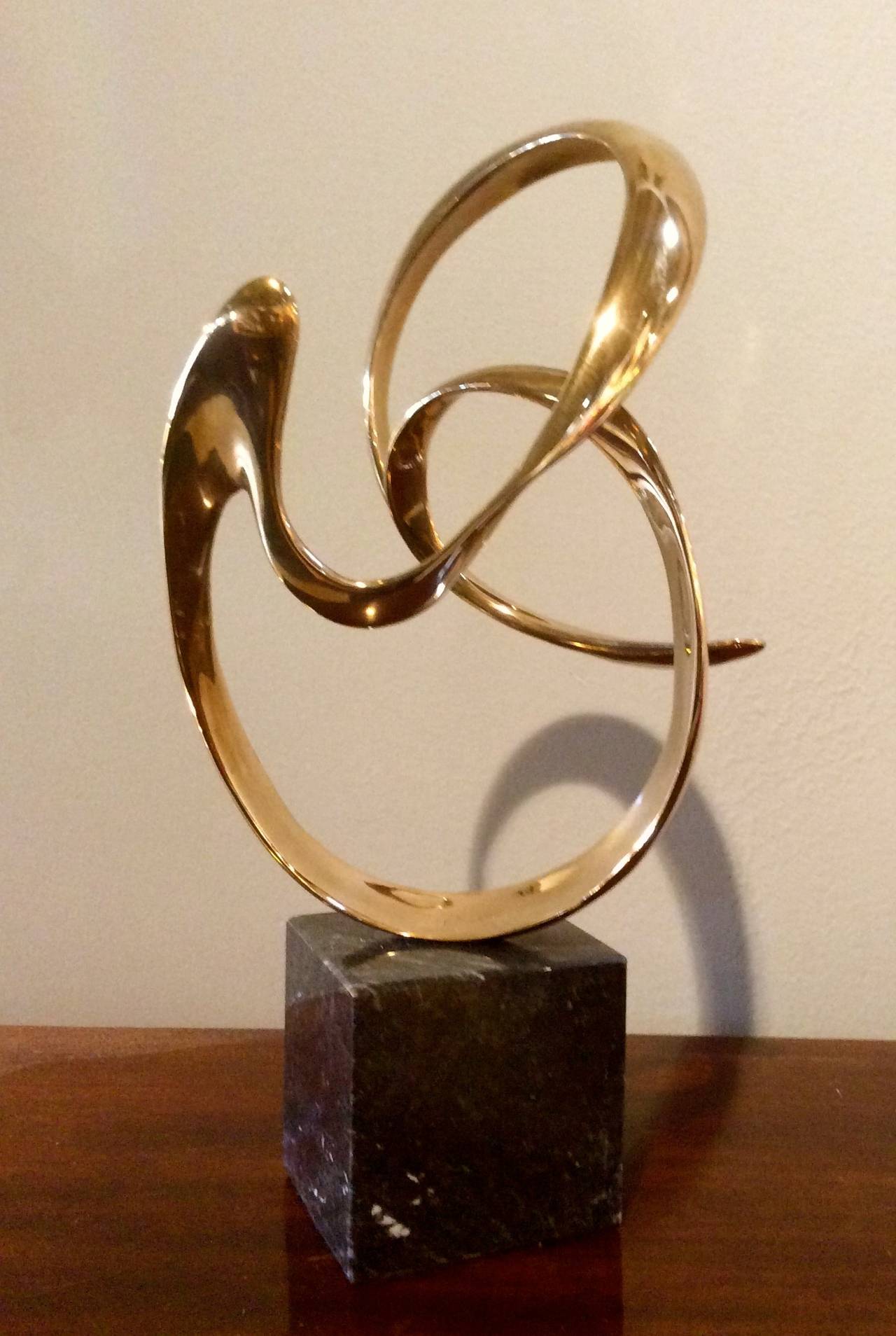 Lyrical bronze abstract sculpture by noted artist Tom Bennett, signed, dated 1987, and numbered 94/150. 
Mounted on a solid 3.5