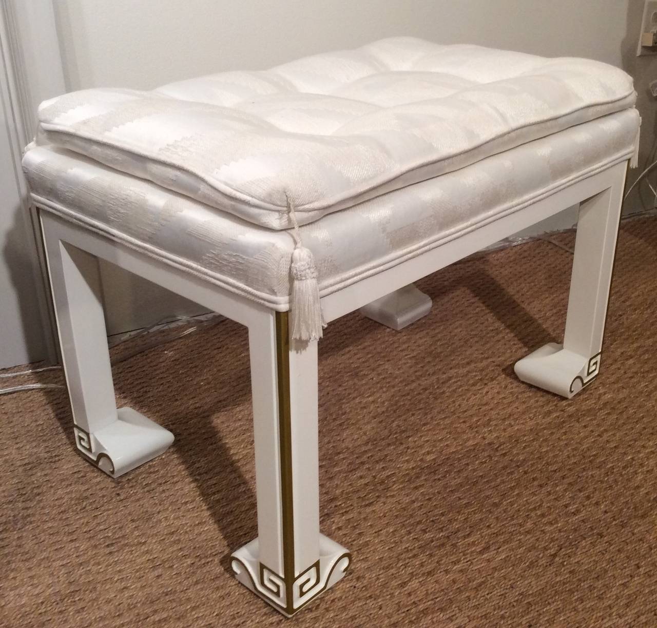 Chic newly lacquered bench or ottoman base, in a warm white tone, with gold painted Greek key design. Button tufted tone-on-tone original upholstered cushion top, with similar tonal white tassels from all four corners. Base is excellent and