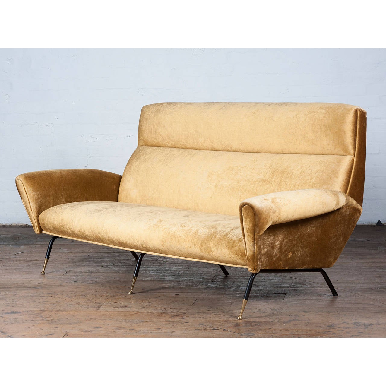 Mid-Century Italian, gold velvet, three-seat sofa designed in the style of Gio Ponti in the 1950s. Features painted black metal legs tipped with polished brass. A great example of the luxurious and glamorous Italian design of the period.