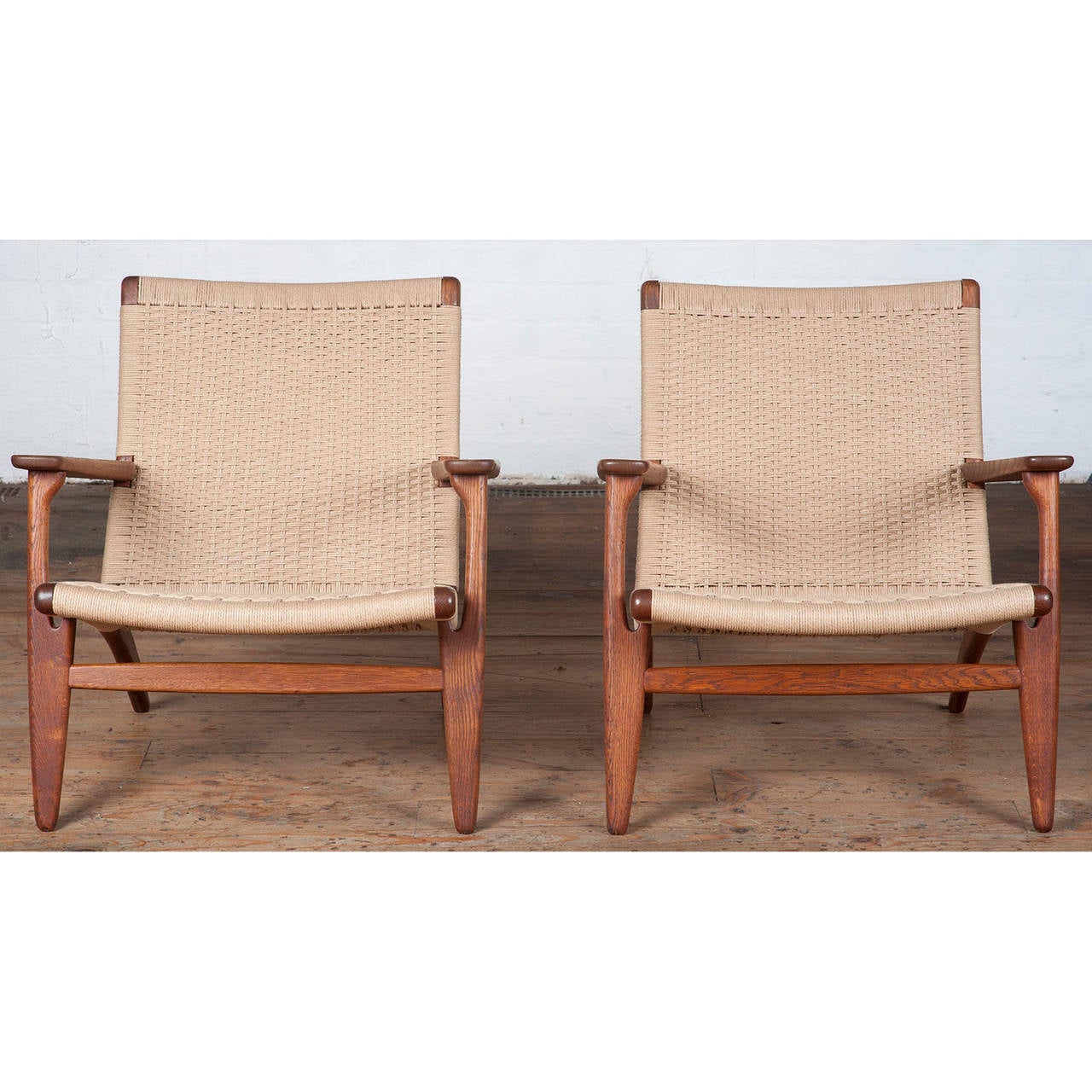 A stunning pair of Danish CH25 armchairs in oak by Hans J. Wegner for Carl Hansen & Son in 1950. Renowned for his chair designs in particular, Wegner's designs epitomise the mid-century Scandinavian aesthetic. The CH25 features broad armrests and a