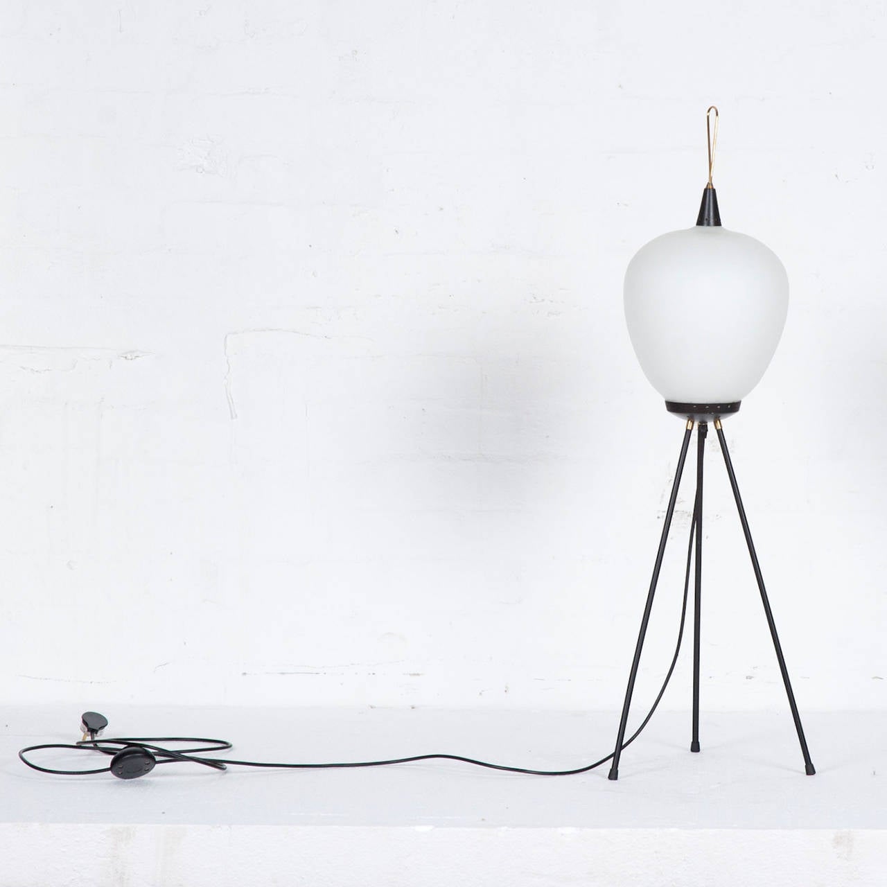 Mid-Century Italian glass lantern floor lamp sitting atop a slender tripod base. Very much in the style of Gio Ponti. This lovely lamp features black metal fittings and brass trims. Featuring a handy floor foot-switch, this lamp would be an