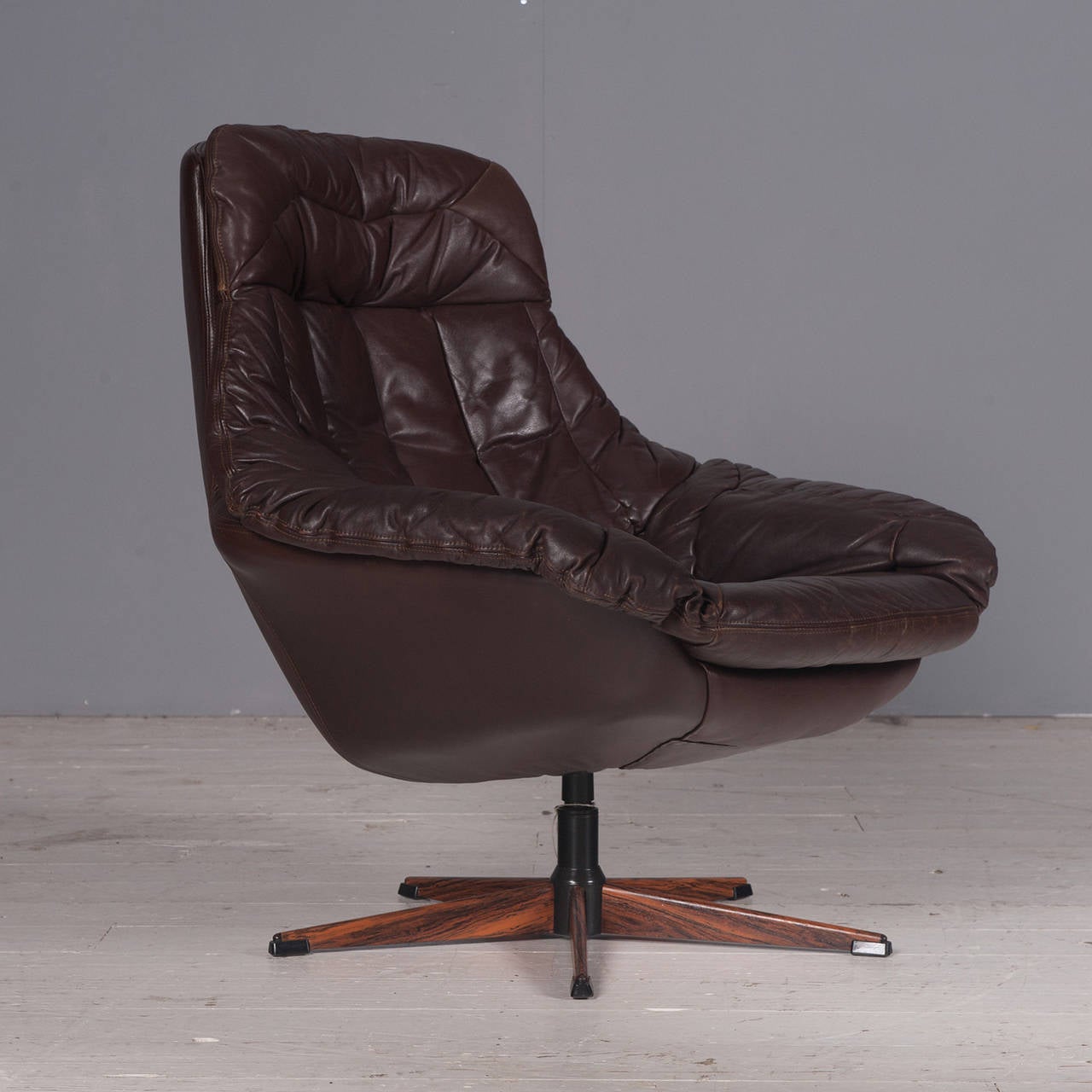 Beautiful rich chocolate brown leather swivel chair by H. W. Klein with a faux rosewood base. Magnificently comfortable, this chair is created relaxing and long conversations.