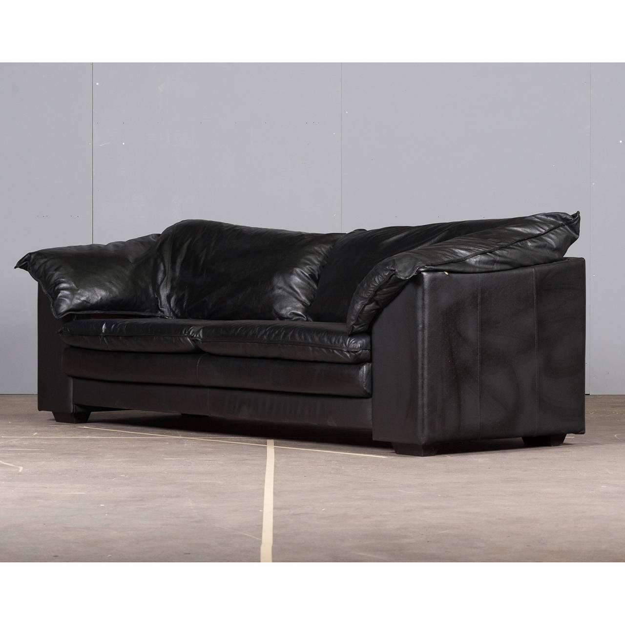 Fabulous Italian three-seater sofa in a rich black leather by Skalma. This is the best of 1980's style and comfort!

The oversized sofa features large, soft back cushions and armrests which fold in for a perfect level of relaxation. There is also