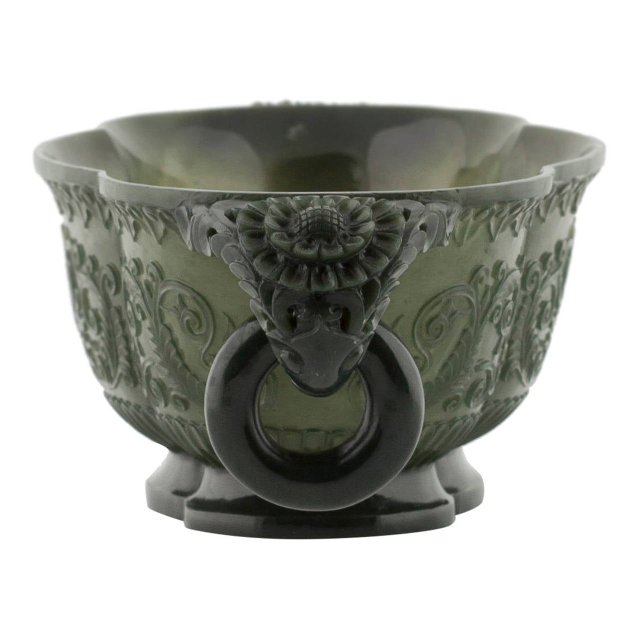 Elaborately hand-carved table centre piece in spinach jade, featuring curved handles retaining circular jade rings, scalloped neck and matching base. Three curved mottled jade panels feature botanical carvings and complimentary carved borders. When