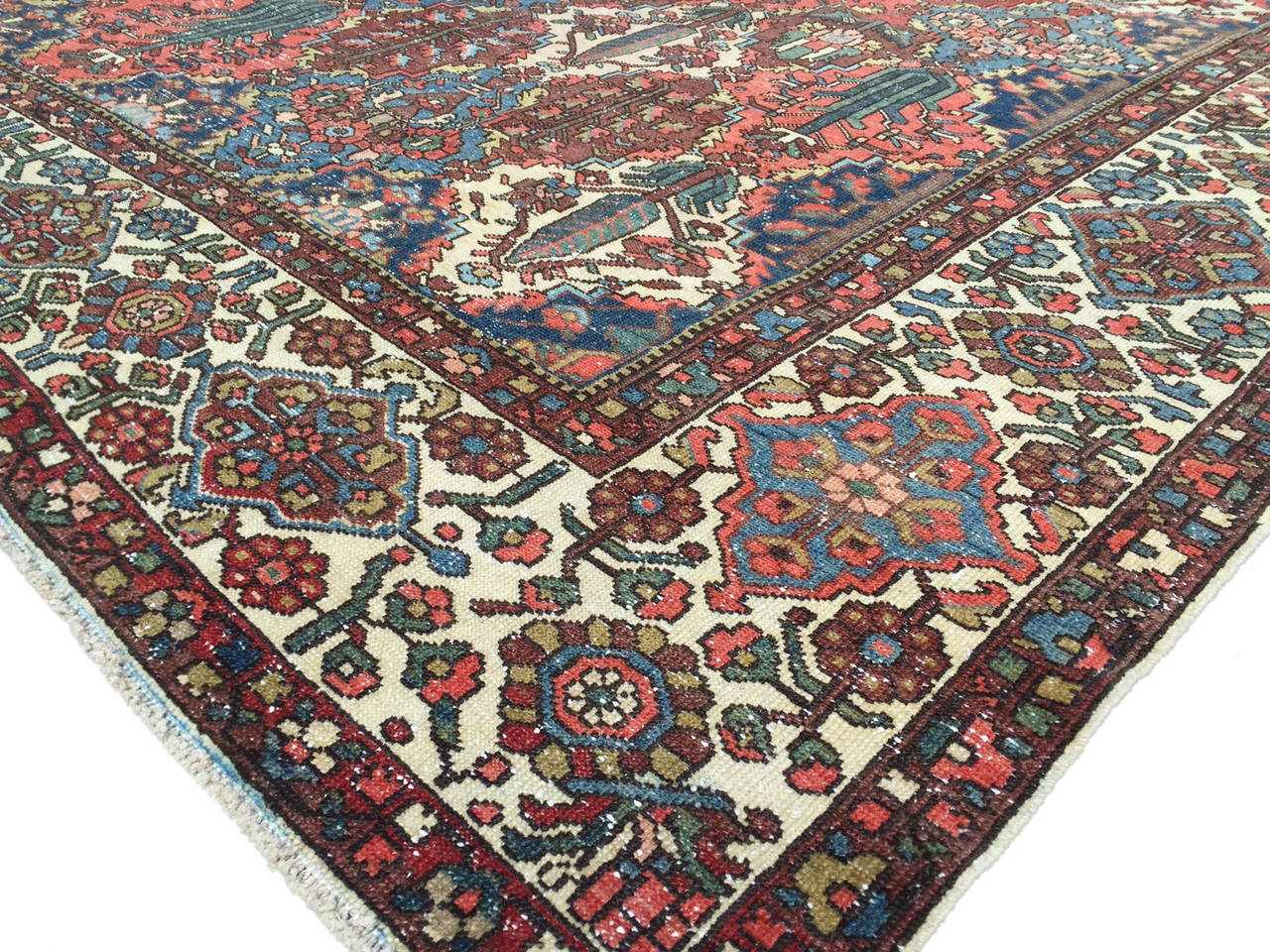 A beautiful tribal influenced antique Persian Bakhtiar featuring a beautiful all-over garden design with a magnificent border with ivory, indigo and red shades throughout.
