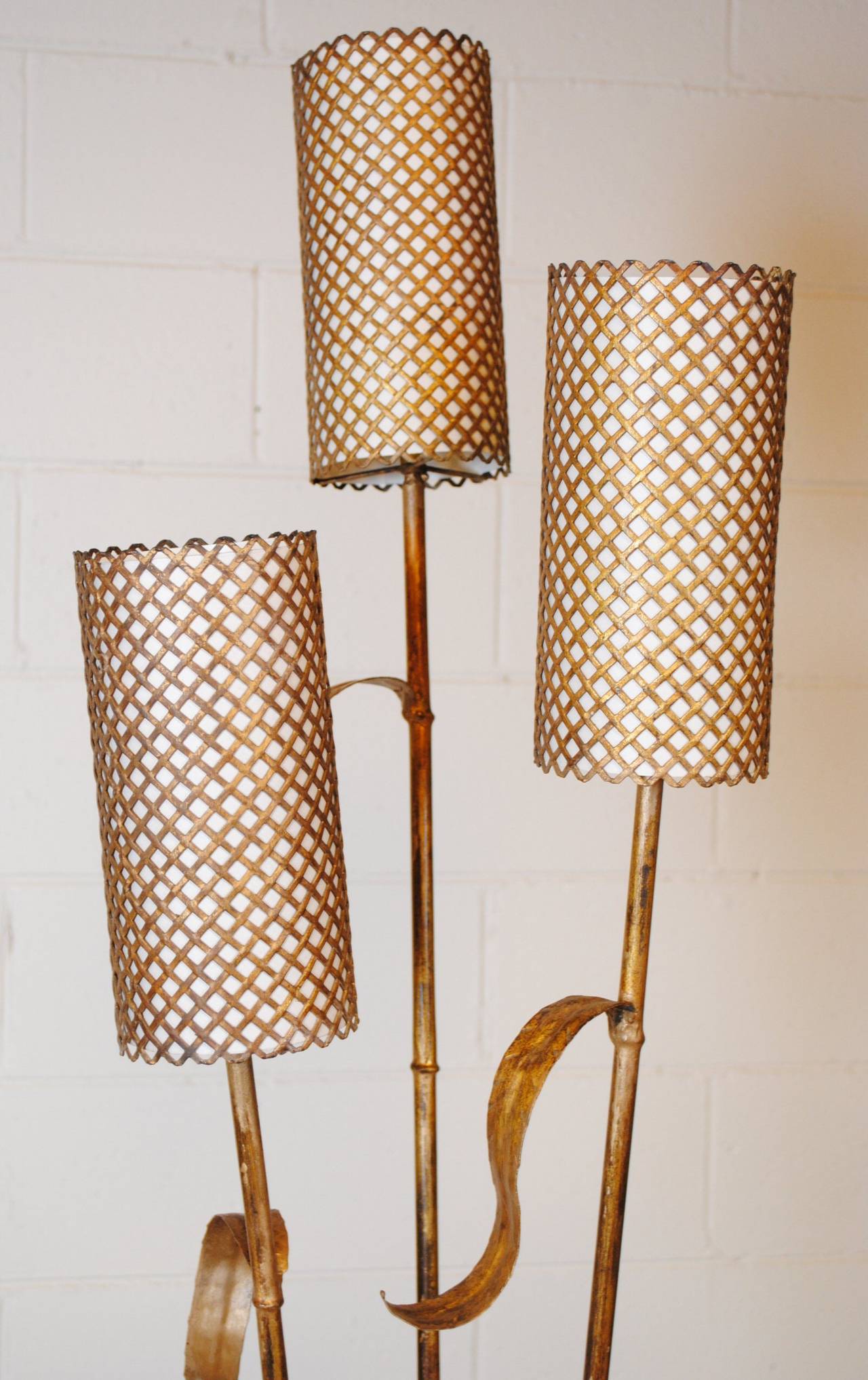 Vintage French gilt standard lamp with three branches in the form of bamboo stalks, the shades are of parchment behind perforated metal. A sweet piece dating from the 1950s.