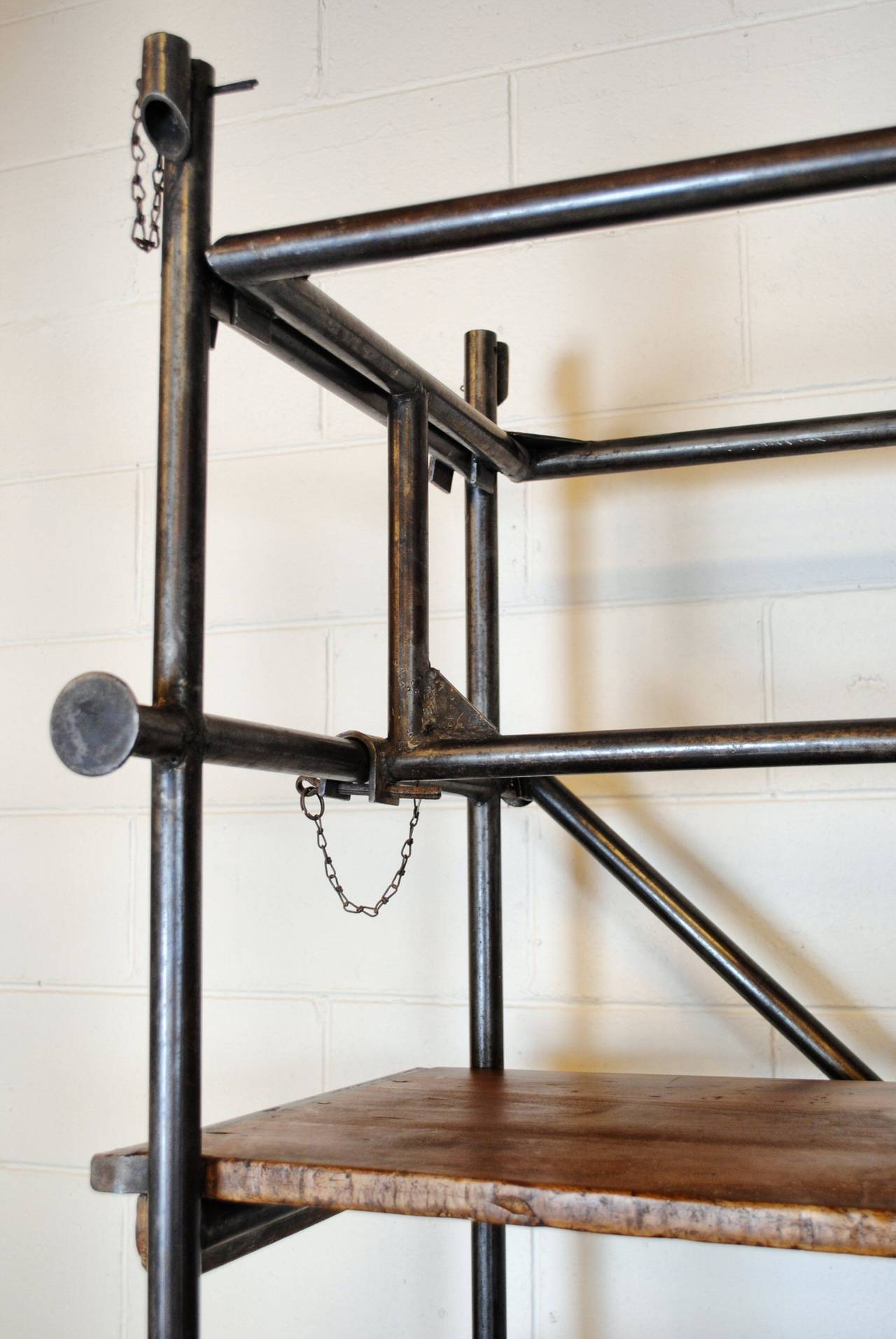 French Industrial shelving unit in tubular steel with solid walnut shelves. One side of the piece has two castors at the base. A wonderful piece for a kitchen or living room.