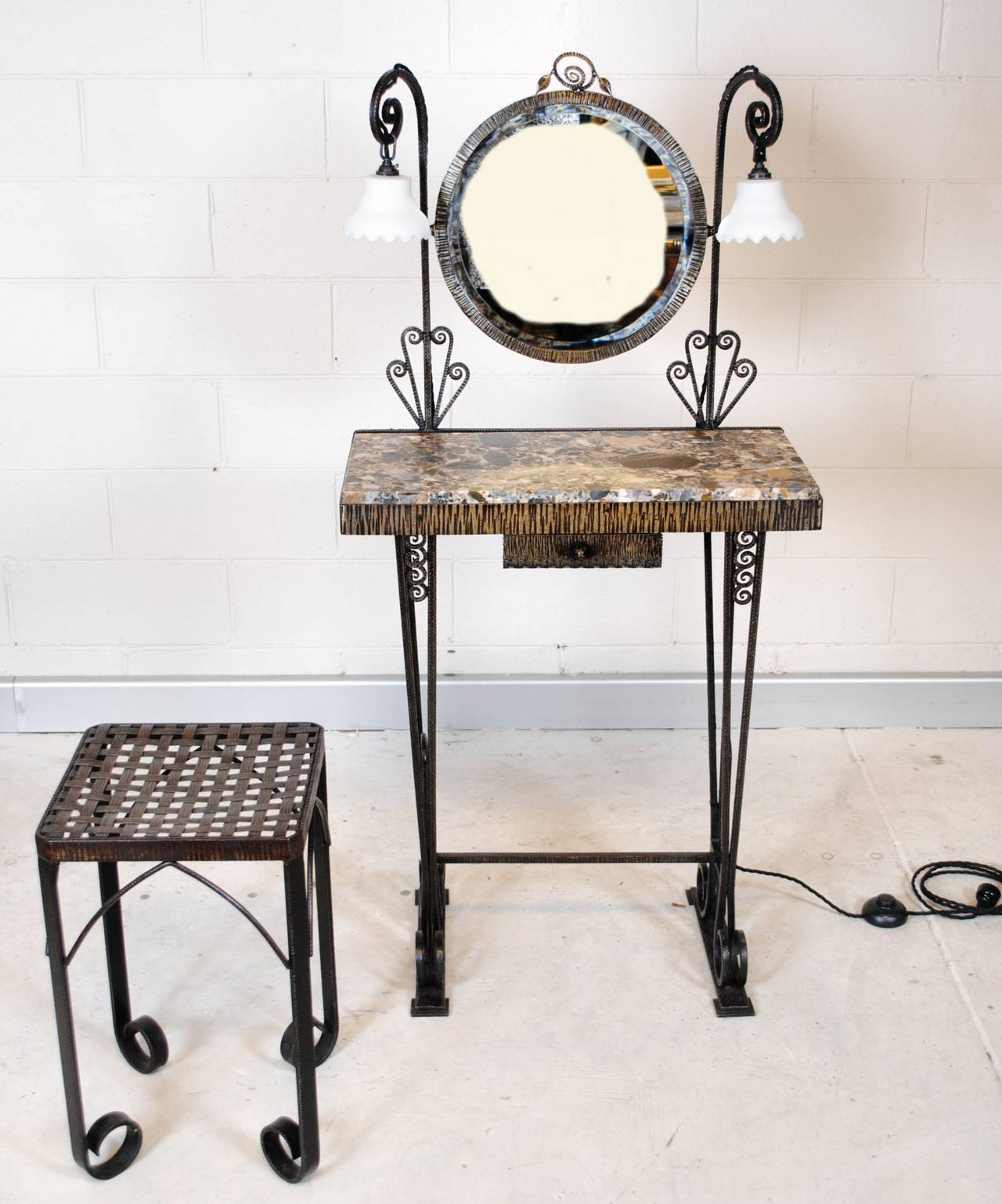French Art Deco wrought iron vanity or dressing table. Featuring adjustable circular mirror with lights on either side, marble plate and small drawer. The seat has a wonderful basket weave to top. The set dates from the late 1920s and would be
