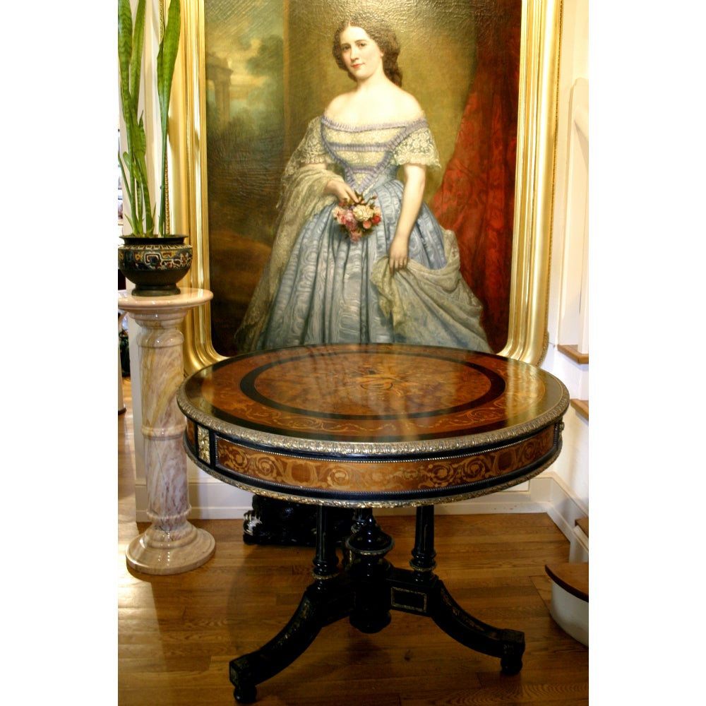 An early 19th century French Empire drum table. This piece features refined marquetry work, with a floral and musical instrument motif, which is surrounded by walnut burl veneer.