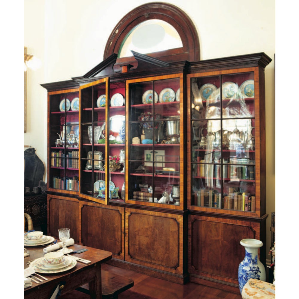 A walnut breakfront cabinet, made in the United States during the Federalist period in the late 18th century. The breakfront design features include the broken pediment, dental cornice and mullion glass doors.