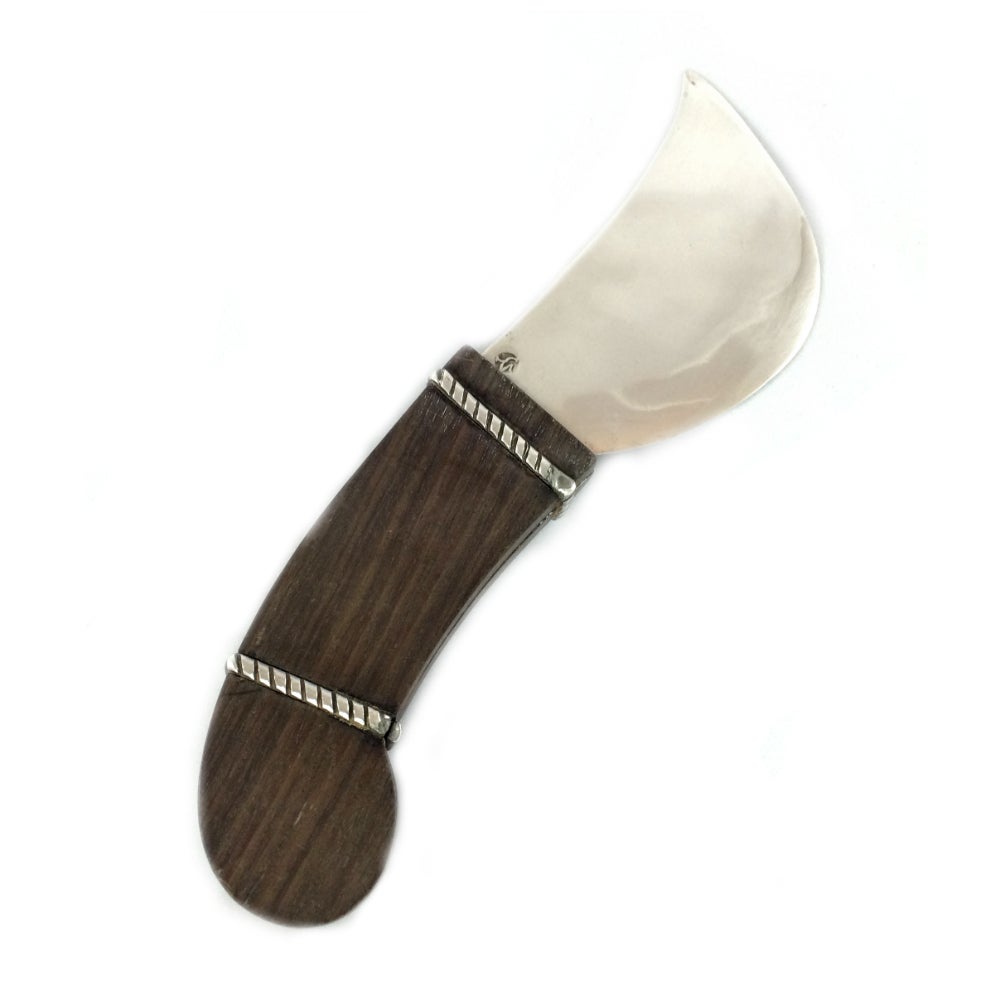 A sterling silver cheese knife with rosewood handle by esteemed silversmith William Spratling. Spratling is often attributed to the success of the Mexican silver industry in the early 20th century, and proudly used Mesoamerican motifs in his designs.