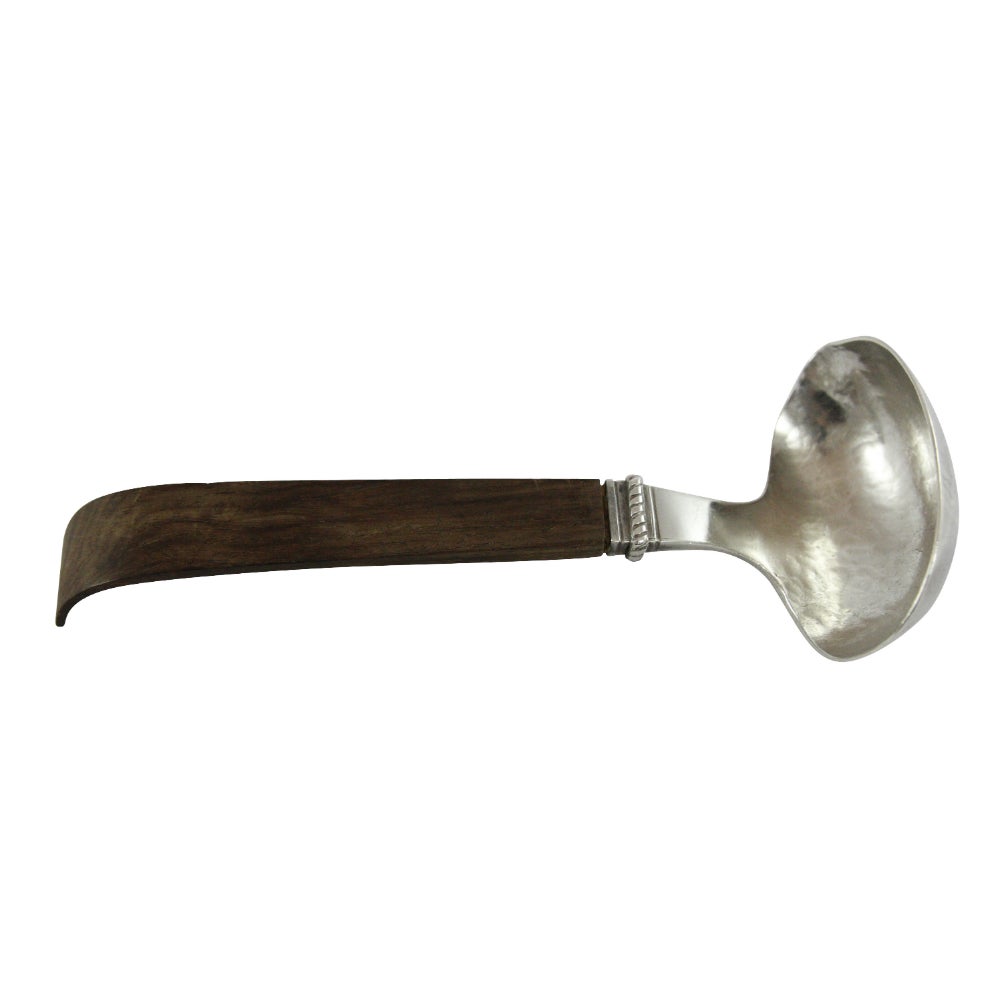 A handcrafted sterling silver, hand-hammered ladle with rosewood handle, by William Spratling. Spratling is often attributed to the success of the Mexican silver industry in the early 20th century and proudly used Mesoamerican motifs in his designs.