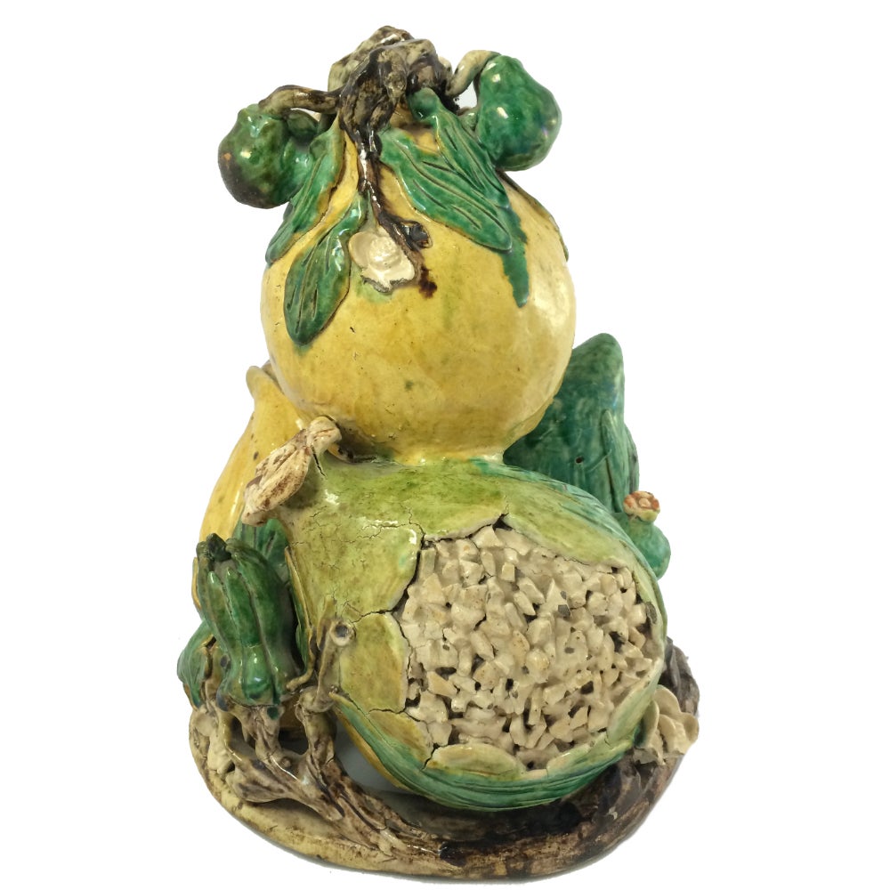 This rare and unusual Chinese stoneware offering would have been crafted in the 17th century to be placed next to a shrine or temple. The piece portrays four large fruit in green, yellow and aubergine, which are attached to a branch which forms the