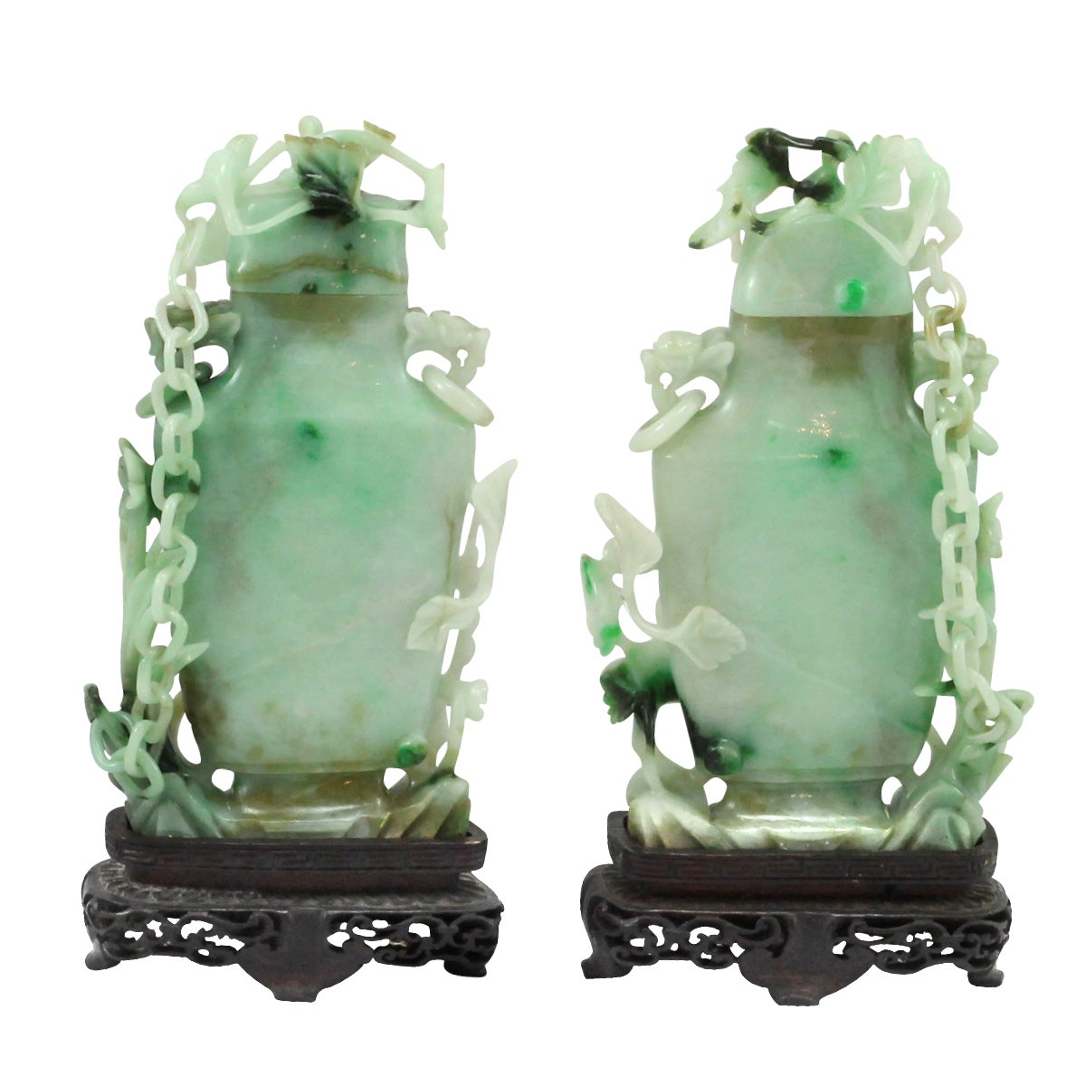 A pair of early 20th century Chinese carved jadeite lidded vases. These specimens have each been expertly carved from a solid piece of jadeite, with incredible attention to detail paid to the fine chain which links the lids to the base of each vase.