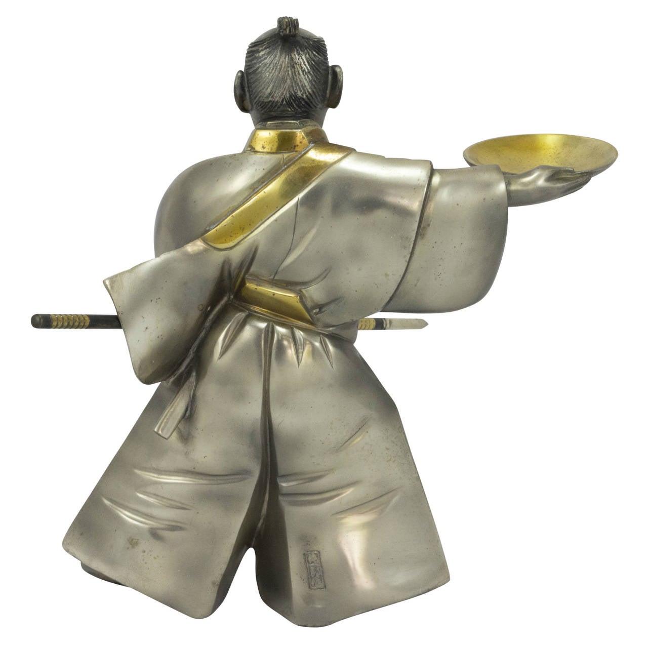 An Art Deco style Japanese samurai figure in silvered bronze. The figure is wielding a spear and has a sheathed katana in his obi. The piece features gilding to his sash, bowl and weapon decorations.