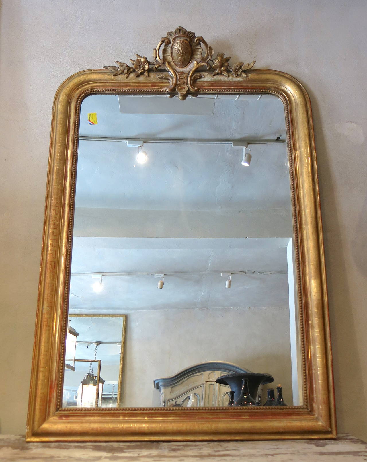 Antique French Louis XV mirror with cartouche, original old silver glass, detailed carvings, beaded frame, Greek key motif, gilded with hints of burgundy.