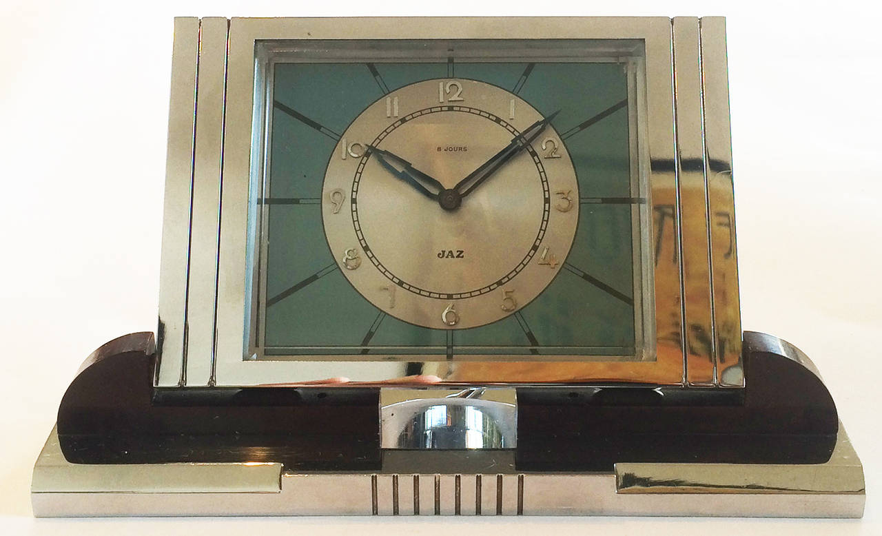 Art Deco Desk Clock, Eight Day mechanism with alarm, in Chrome and Palissandre Wood, by Jaz, France. Radiating “Sunburst” lines, Arabic numerals in Chrome on white enamel, background in sky blue with black enamel details, name “JAZ” in black enamel