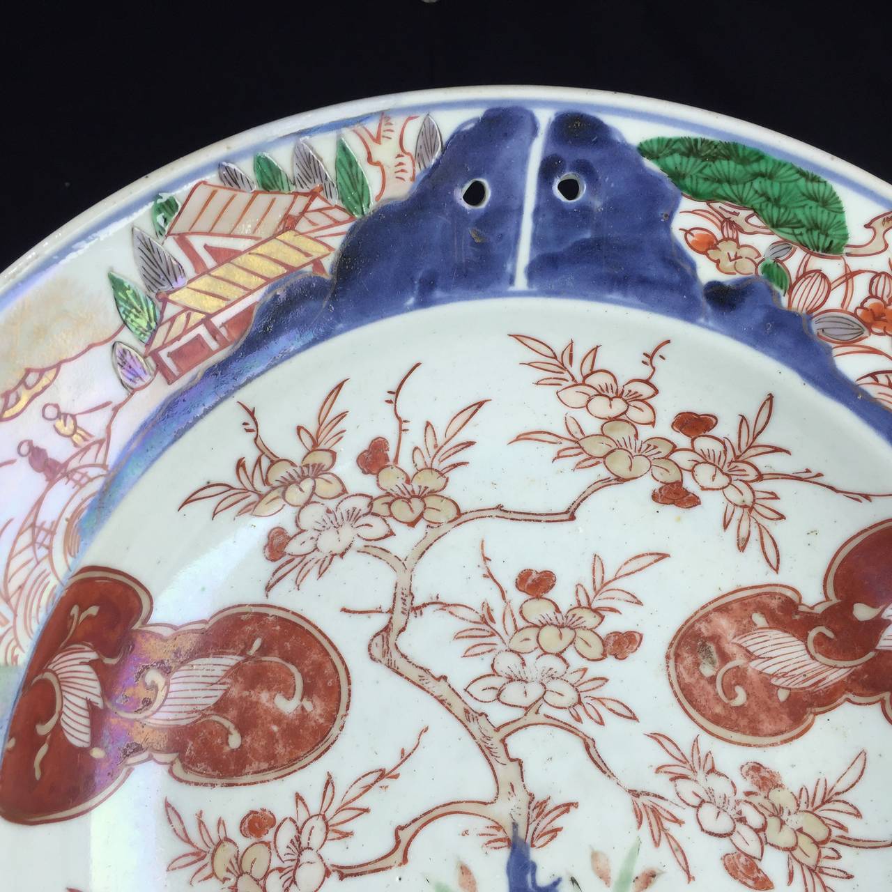 Rare Japanese Imari barbers bowl, made for the Western market, decorated with a vase of flowers on a table, the border with panels of garden scenes, the rim with two holes for hanging it up,
Circa 1680.