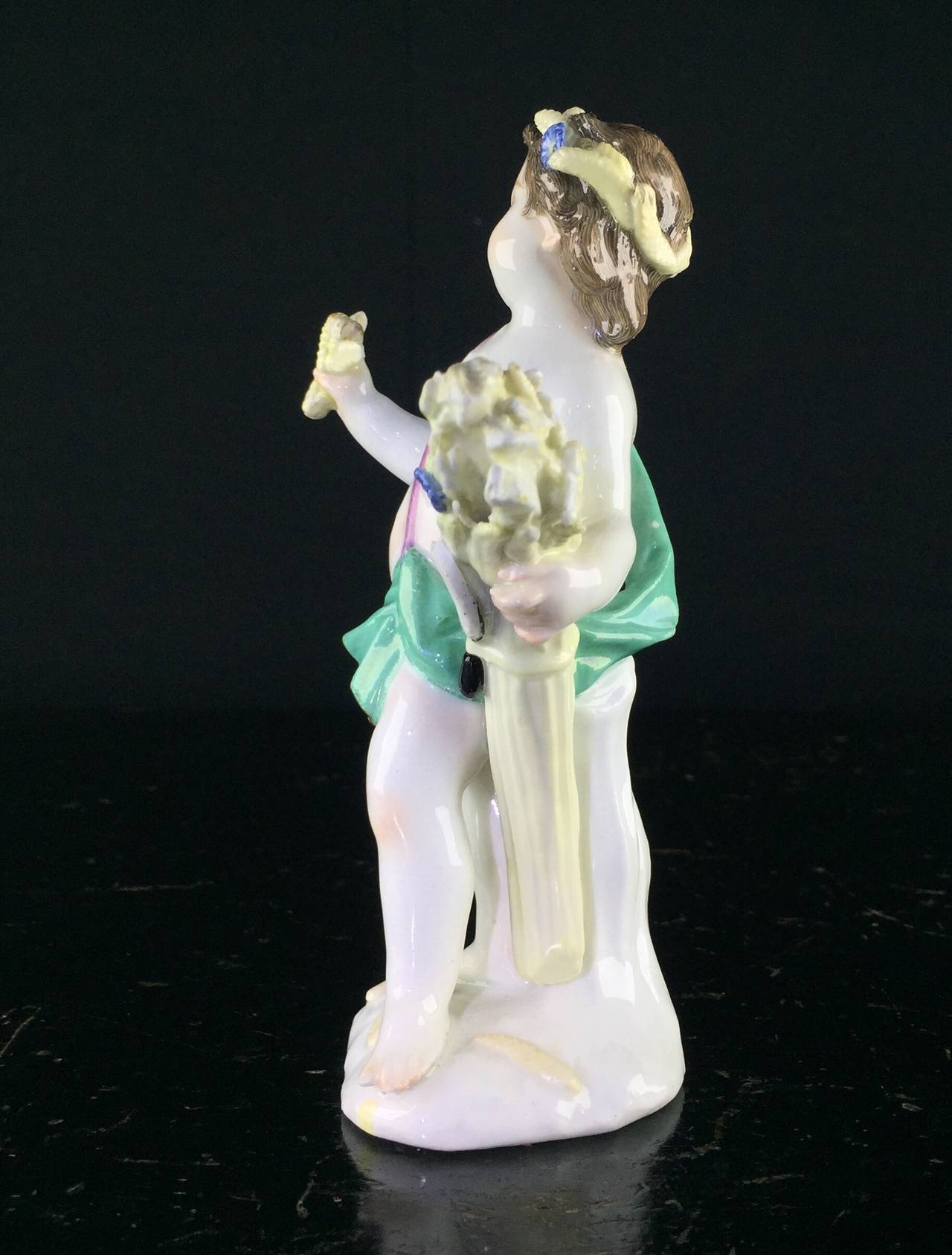Meissen figure of a boy representing Summer, shown standing with a twist of turquoise cloth, a large bound sheaf of wheat with sickle to one site, a corn of wheat in his outstretched hand, more wheat and flowers in his hair, by J J Kandler, circa