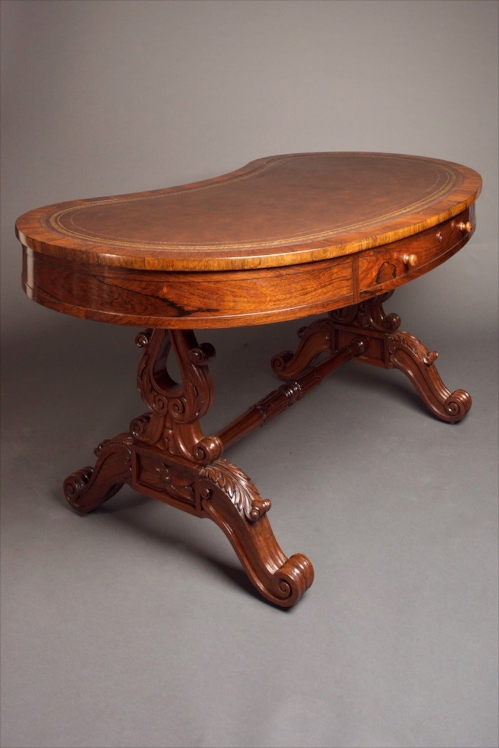 Rare William IV Kidney Desk in Rosewood.

William IV Kidney Desk, English, circa 1830s. The desk is supported upon lyre shaped trestles connected by a turned and carved stretcher. Tooled leather top with one drawer the other side having a faux