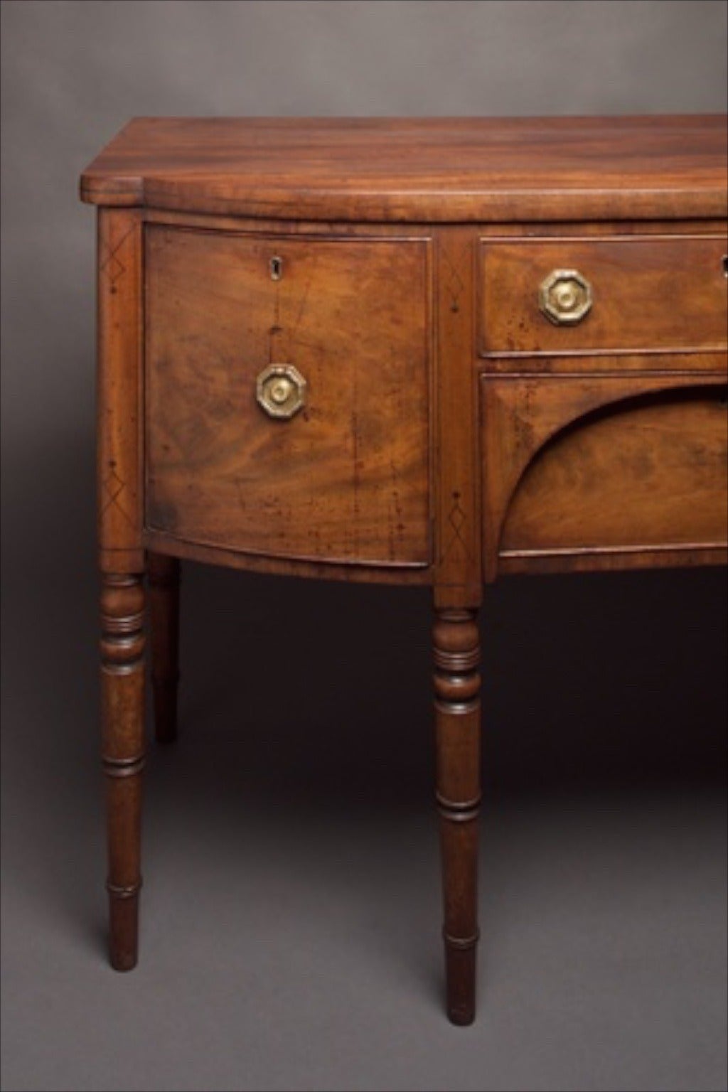 5,850.00.

A George III mahogany bow front sideboard with one cupboard, two drawers to the frieze and a drawer to the other end. The ebonized string inlay dating the piece to after the death of Nelson. The whole standing upon turned legs. The
