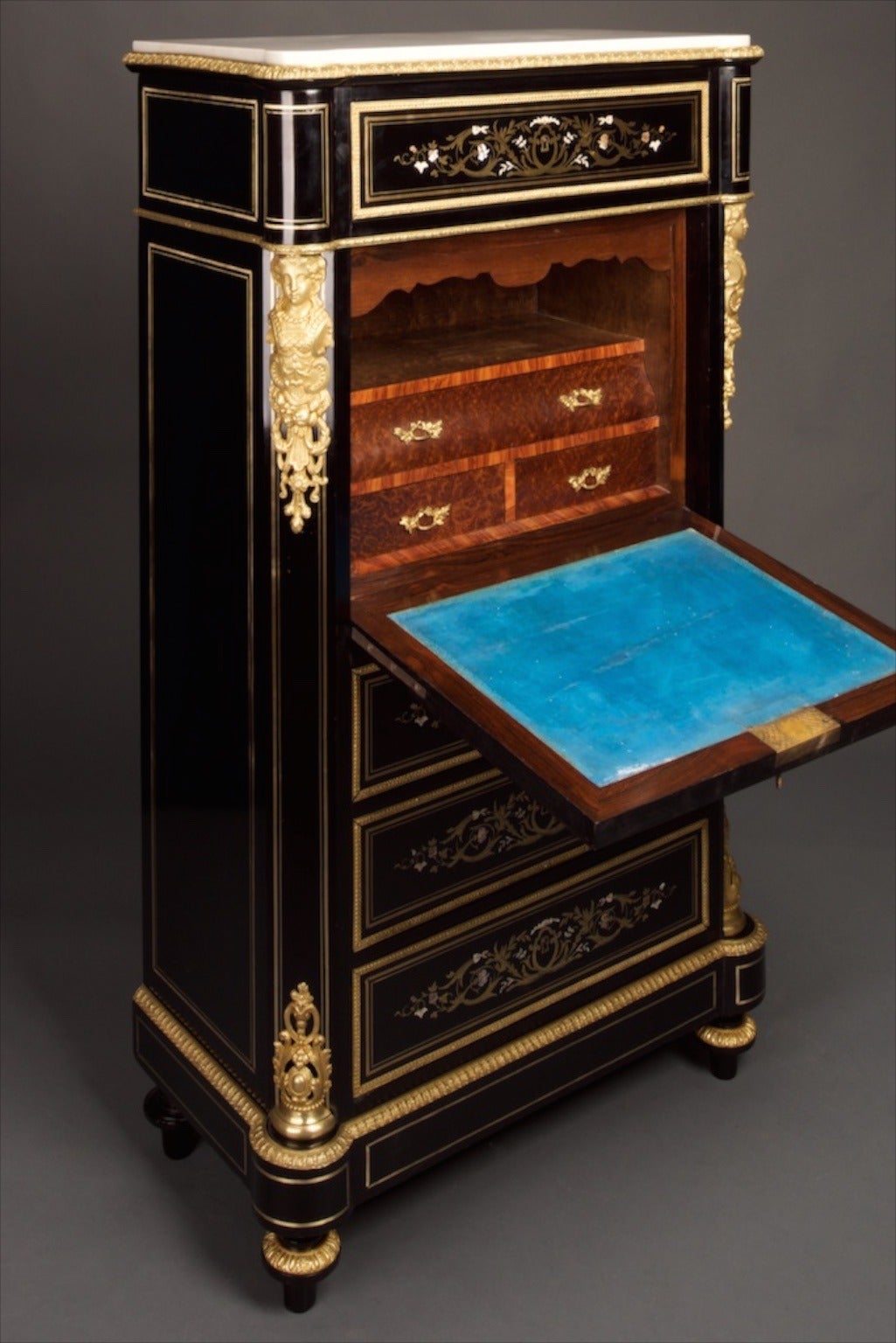 This secretaire is of desirable compact size and has recently undergone museum quality refurbishment. The unit comprises of four full width vertically stacked drawers all with raised gilt perimeter mouldings and with intricate inlays of brass