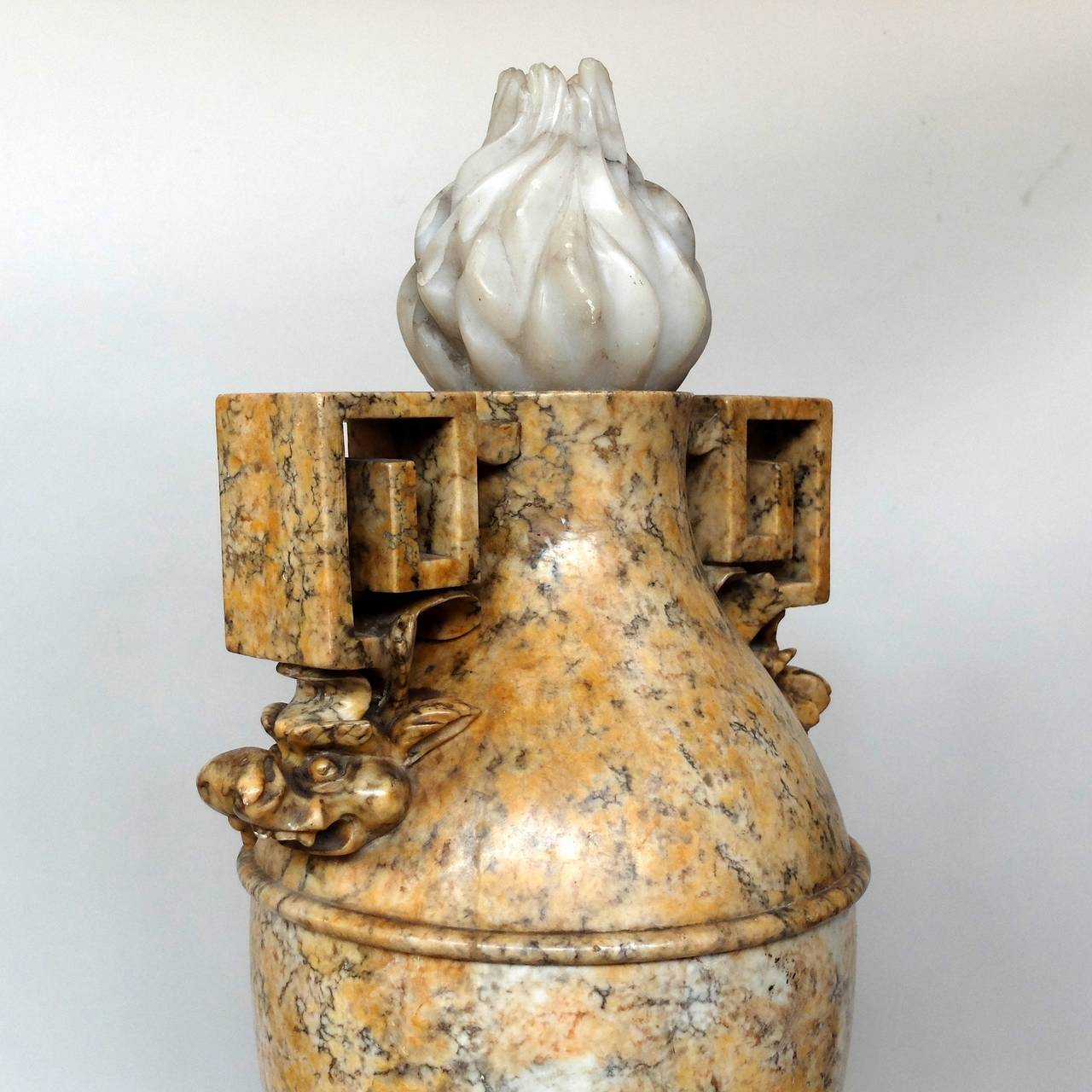 In the form of a flame-topped urn, with stylized handles.