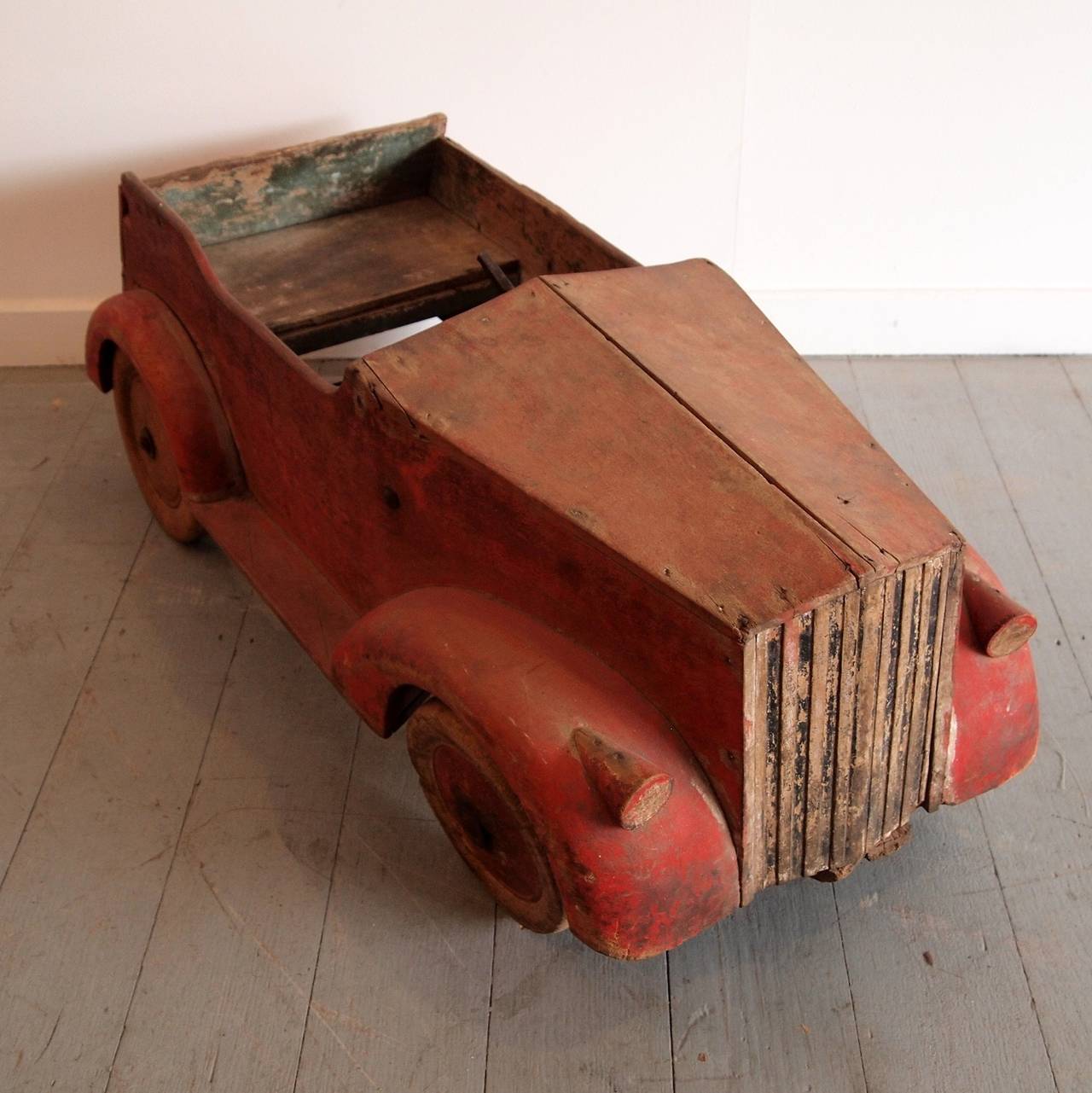 Beautiful handmade pedal car in the style of a Rolls Royce, with original red paint on the exterior, green painted interior and traces of black paint on the radiator. Turned timber wheels (two are later replacements).