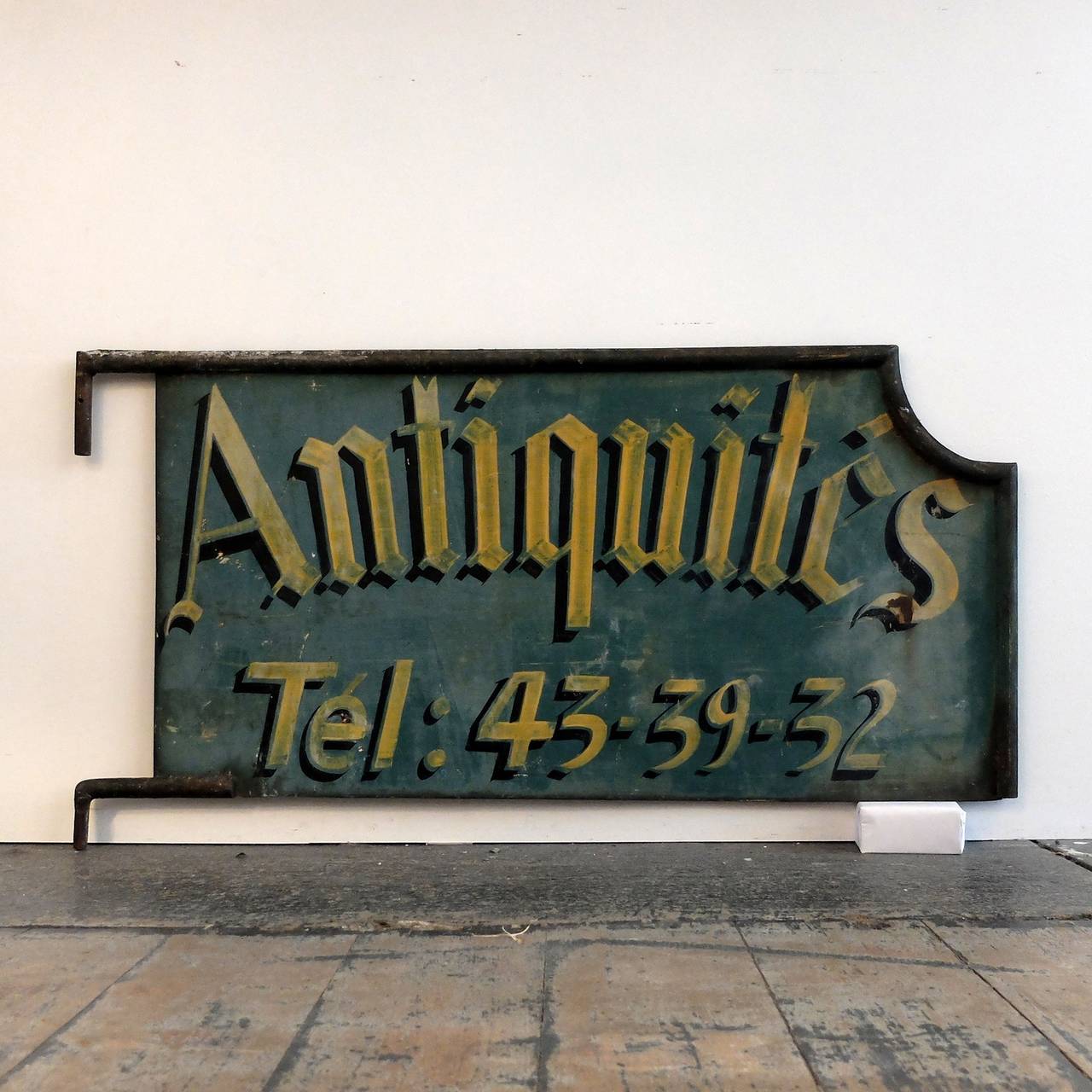 Hand-painted in Gothic script 'Antiquités' with the shop's telephone number below. 
Double-sided (reads the same on both sides).