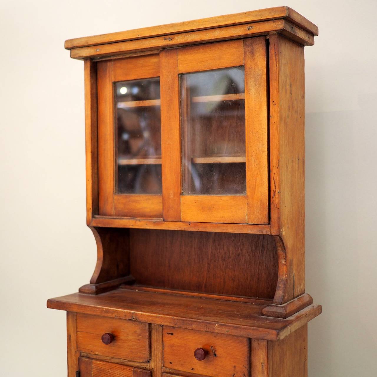 Most probably an apprentice piece, or built for a child. Typical form, with glazed doors above, drawers and cupboards below.