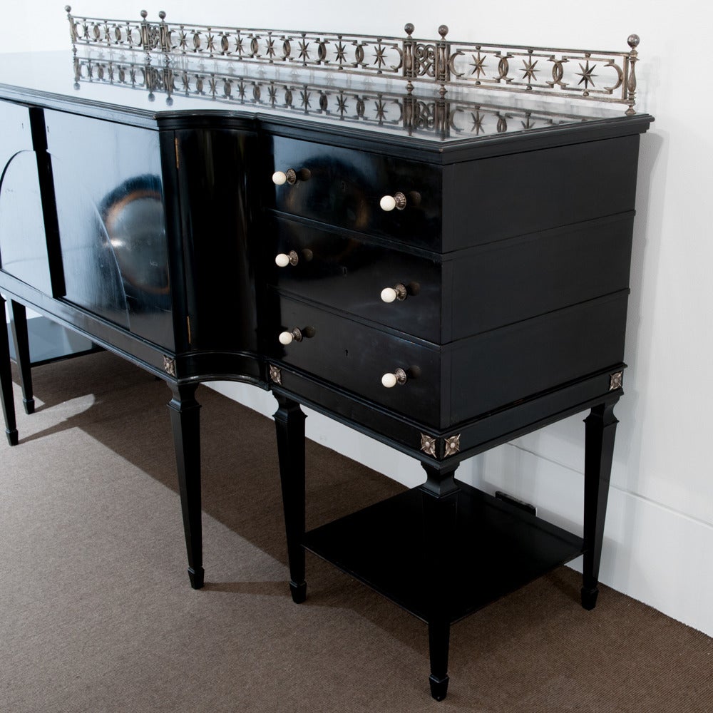 1940s black lacquered buffet the finely cast gallery of turned balusters framing stars above the breakfront top the central doors with an arched panel flanked by fitted drawers the moulding highlight superb quality and workmanship.