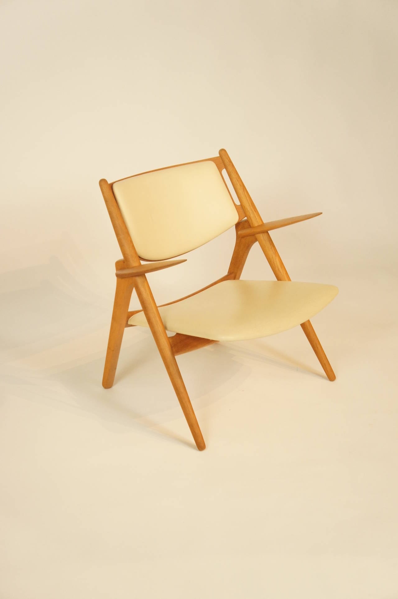 Hans Wegner CH 28 Sawhorse Chair.  Restored Solid oak frame.  Original cream leather upholstery, foam in seat and back has been replaced.
** Shipping quoted is air freight.  If you would like us to quote for sea freight please contact us.