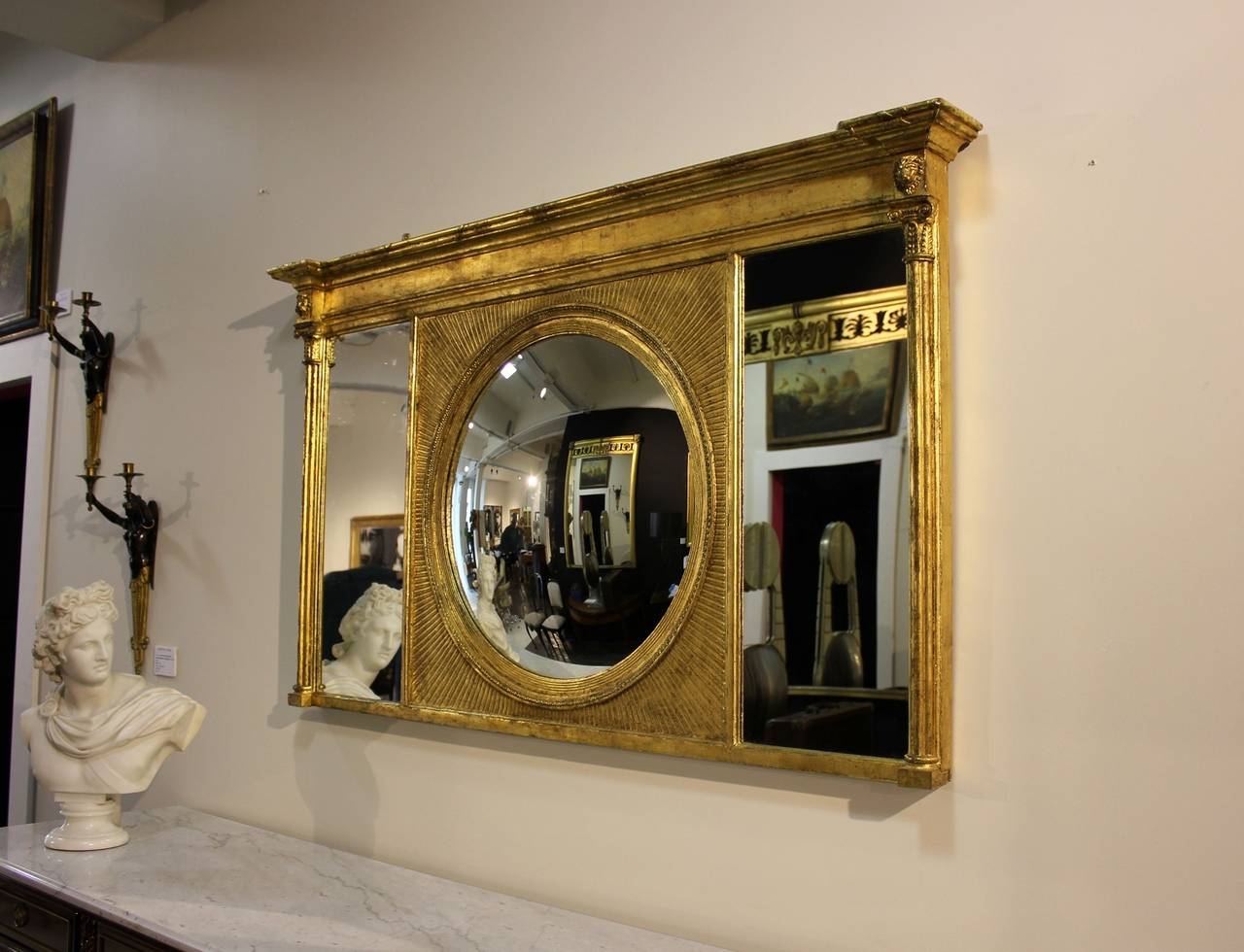 An unusual and rare late Geo III and Regency period oil gilded mantel Mirror by Thomas Fentham London, [trade label to reverse] with starburst convex centre section, flanked by mirror sections to cluster columns, Ionic detail with lion mask motif