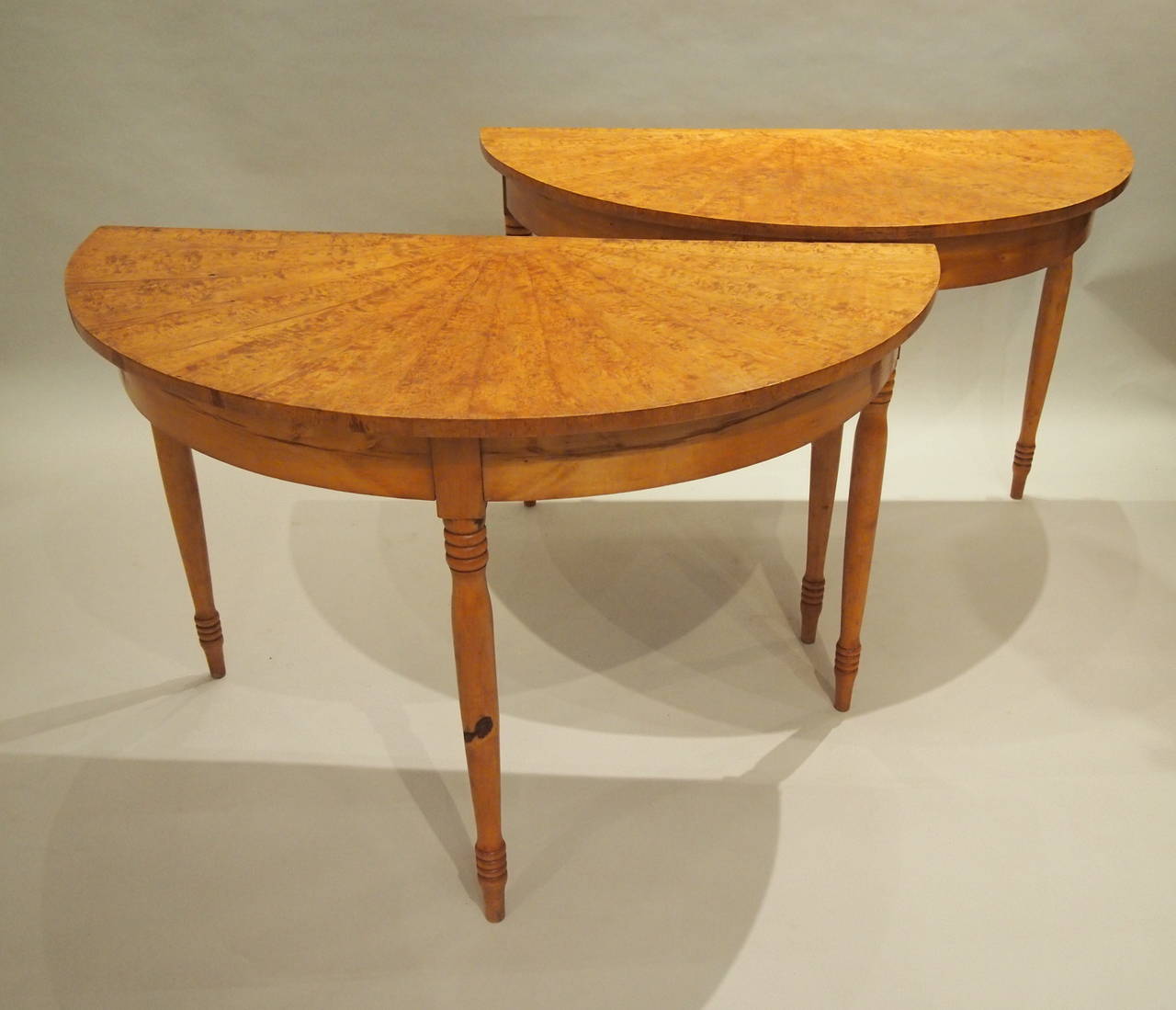 Wonderful Swedish table of two demilune halves with Karelian birch veneered top that has been executed in the image of a sunburst. The table legs are solid birch. They can be used together as a small dining table or separately on either side of a