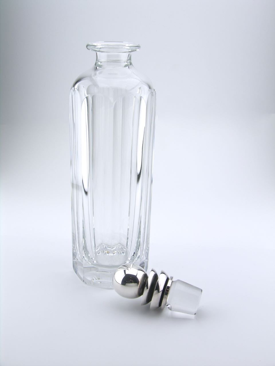 A rare example of a Georg Jensen decanter with a pyramid design stopper. The tall elongated decanter combines a simple facetted crystal body with a silver cased crystal stopper. 

The pyramid pattern of a combination of three raised tiers