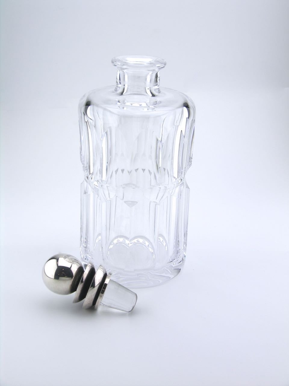 A rare example of a Georg Jensen decanter with a pyramid design stopper. The medium height decanter combines a simple facetted crystal body with a central concave section forming a hand grip around the decanter with a silver cased crystal stopper.