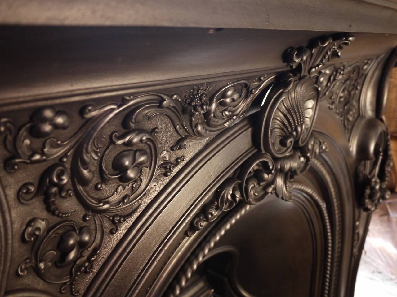 Superb quality Mid-Victorian English cast iron fire surround complete with register in the Rococo style. Kite mark dated to 1852. Finely cast detail in the fruit laden swags, floral breast plate and the scalloped central shell motif.