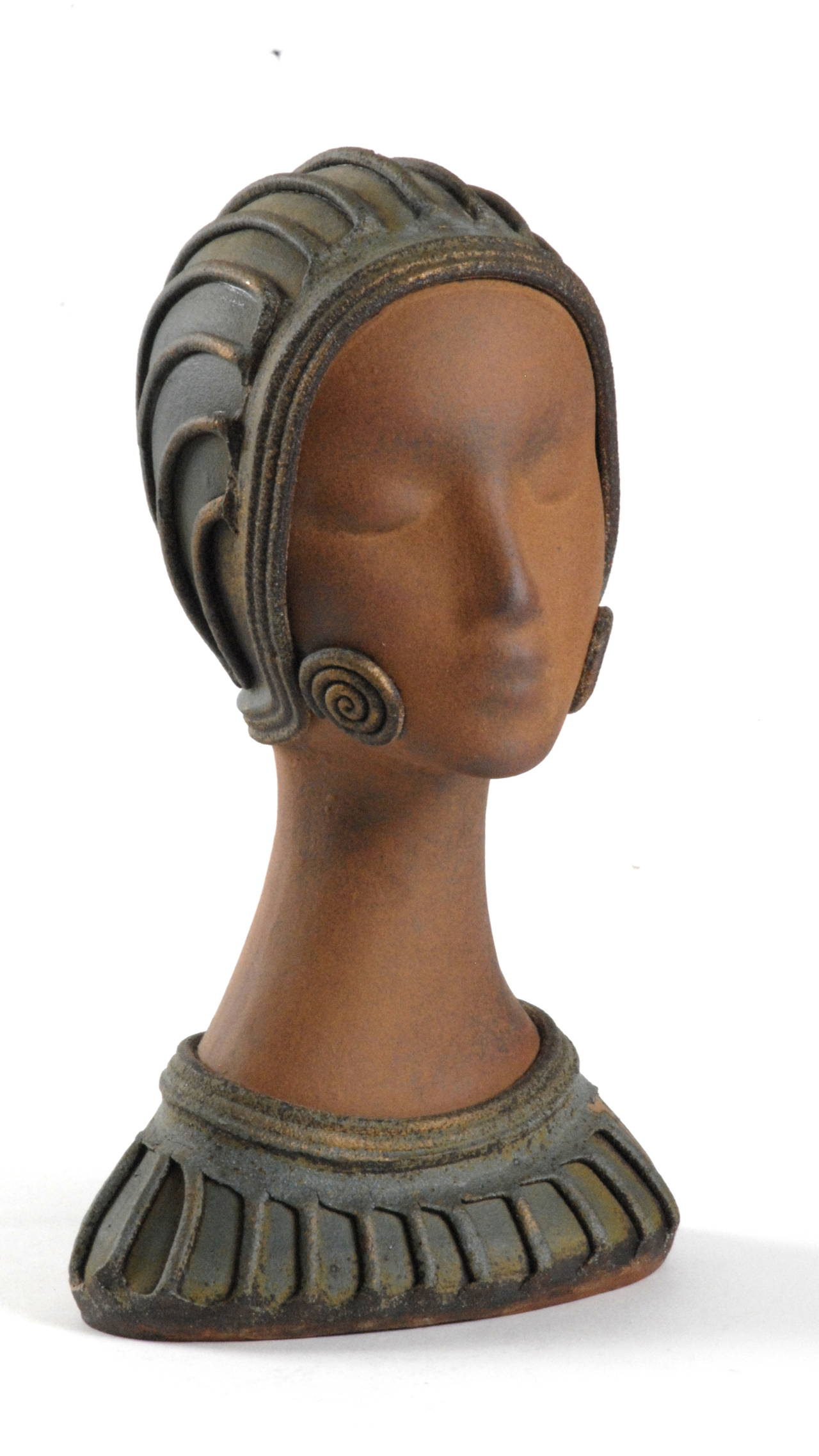 An elegant Art Deco style female head, probably dating from the 1950s-1960s.
Made from terracotta it is finely detailed and conveys a serene and stylish young female.
Applied ribbing for the hat and around the shoulders and by the bottom of the
