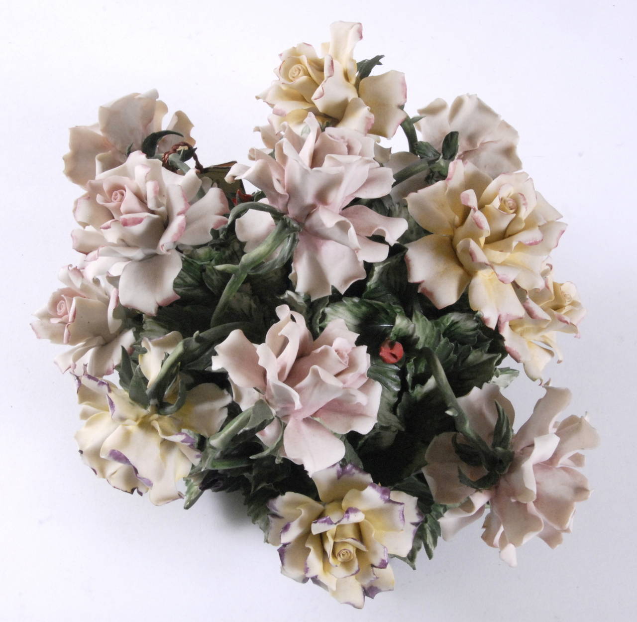 A Capodimonte, Naples, Italy, porcelain handmade table center of an arrangement of pale pink & yellow roses, circa, 1950. Each component handmade and assembled and then hand-colored in pale pink and yellows with contrasting deep green foliage. In