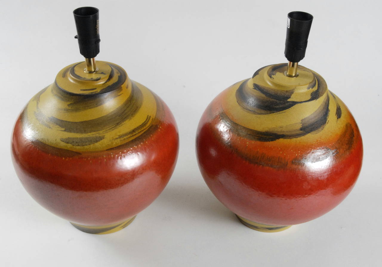A lovely pair of Alvino Bagni ceramic lamp bases in tomato red with yellow tops and bottoms with 'zebra' stripes, stamped Italy, circa 1970. In 'as new' condition.