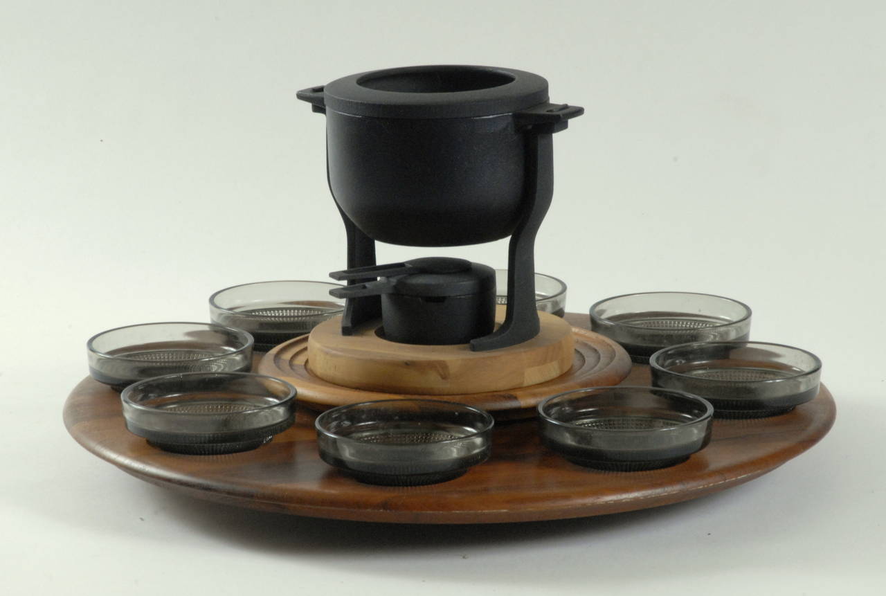 A large fondue set with a 'lazy susan' teak stand holding 8 glass dishes, centered by a static stand for the fondue pot and burner. The teak stamped 'Digsmed Denmark', c.1960.
The cast iron pot is white enamelled on the interior and in perfect