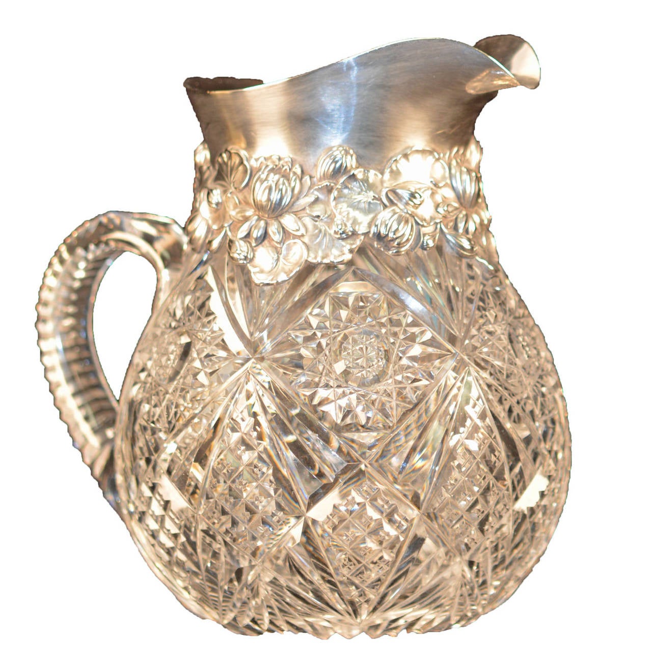 American brilliant period cut-glass pitcher with large Gorham sterling mount. Rayed hobstars with strawberry diamond, and fan cover the body. Notched handle and rayed base. Large heavy sterling rim with Art Nouveau water lilies and leaves. Gorham