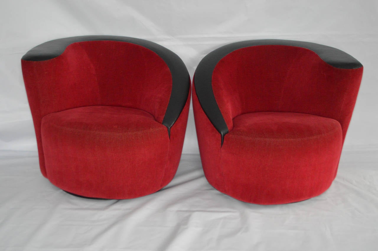An excellent pair of Vladimir Kagan Nautilus swivel chairs.  These chairs feature sloping, asymmetrical backrests. Each chair rests on swivel bases which allow them to rotate 180 degrees and then return to their original position. 

Covered in red