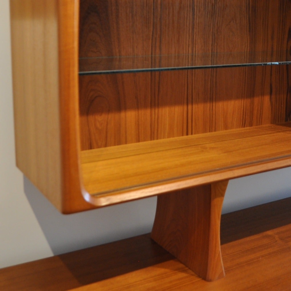 This absolutely pristine example of a danish modern sideboard and china hutch will give you all the storage and display you could want. The hutch has glass sliding doors and sits upon fabulously shaped legs which rest atop sideboard but can be used